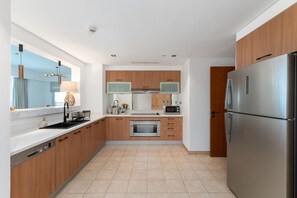 A modern kitchen with wooden cabinets, stainless steel appliances, a built-in oven, and a microwave.