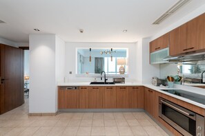 A modern kitchen with wooden cabinets, a stainless steel oven, and a large window.