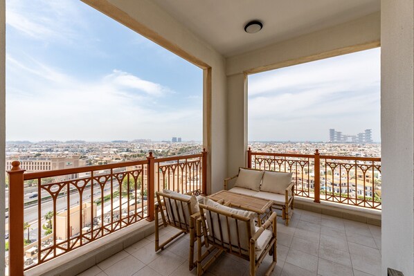 A balcony with a view of a cityscape, furnished with a table and chairs.