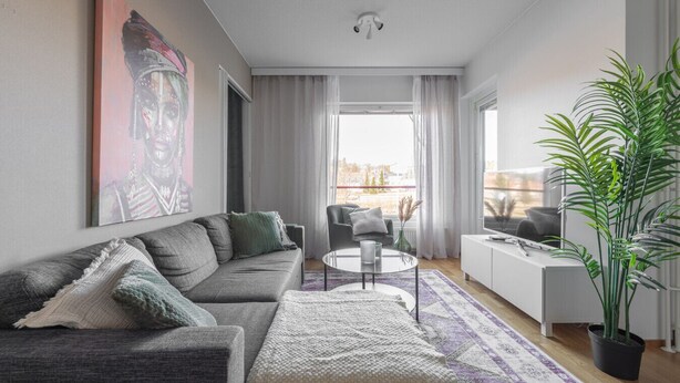 A modern living room with a grey sofa, a coffee table, and a large window with curtains.