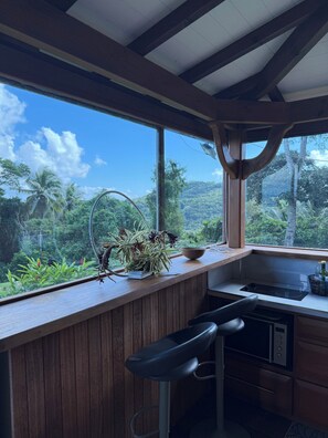A kitchen with a wooden countertop, a sink, and a window overlooking a lush landscape. - Chalet de la plaine (Les Trois-Îlets)
