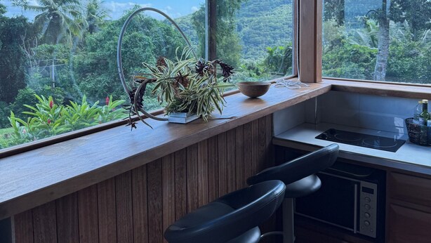 Eine Küche mit einer Holzausziehtafel, einem Spülbecken und einem Fenster mit Blick auf eine üppige Landschaft.