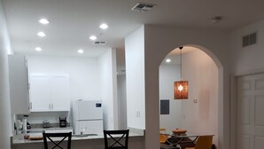 Una sala de estar moderna con un sofá de cuero, una mesa de centro y una zona de comedor con sillas y una mesa.