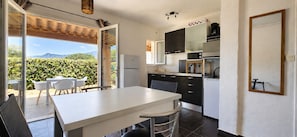 A kitchen with a dining area, a refrigerator, a microwave, and cabinets.