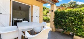 An outdoor dining area with a table and chairs, a covered entrance, and a hedge. - Studio Dolce & Vita A1 with pool and terrace (Propriano)