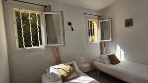 Een slaapkamer met twee bedden, een klein nachtkastje, een lamp en een raam met gordijnen.