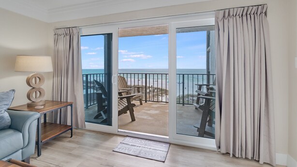 Una habitación con puerta de vidrio corrediza que da a un balcón con vistas a la playa.