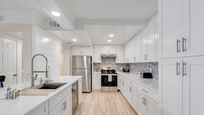 Una cocina moderna con armarios blancos, electrodomésticos de acero inoxidable y un salpicadero de azulejos.