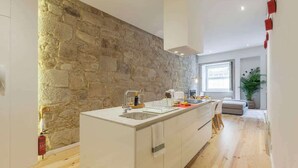 Eine moderne Küche mit einer Wand aus Stein, Holzboden und einer zentralen Kochinsel.