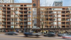 A multi-story building with a brick facade, multiple balconies, and a ground-level entrance with signage.