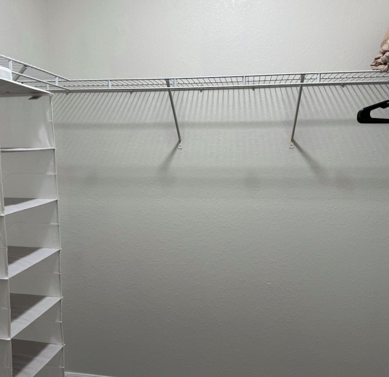 Un placard avec des étagères en métal et une tringle pour suspendre les vêtements.