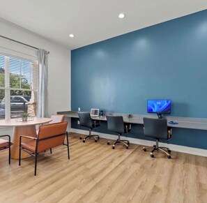 A conference room with a long table, four chairs, a laptop, and a television on the wall. - Heart of Bartram Escape! (Jacksonville)