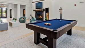 Amplia sala de estar con mesa de billar, asientos cómodos, chimenea y un televisor grande.