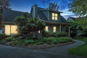 A two-story house with a covered porch, a chimney, and a well-maintained garden.