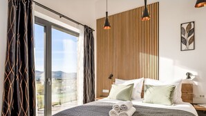 Ein modernes Schlafzimmer mit einem großen Bett, einer Wand aus Holzlatten und Blick ins Freie.