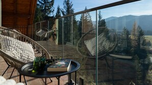 Ein Balkon mit Korbstühlen, einem runden Tisch und einem Buch.