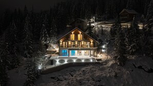 Ein großes, zweistöckiges Holzhaus mit einer markanten Eingangstür und einer sichtbaren Treppe, die zum Obergeschoss führt.