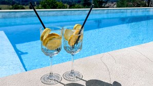 Zwei Gläser mit einem Getränk, Zitronenscheiben und Trinkhalmen am Poolrand.
