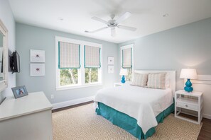 Ein Schlafzimmer mit einem Bett, einem Nachttisch, einem Schreibtisch und einem Deckenventilator.