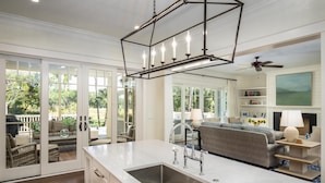 A spacious kitchen with a large island, a dining area with a sofa, and a view of the outdoors through large sliding doors.