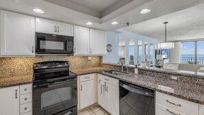 Una cocina moderna con armarios blancos, encimeras de granito, horno de acero inoxidable y lavavajillas.