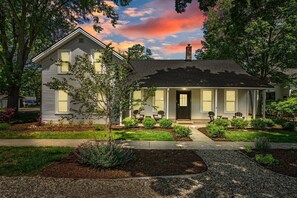A single-story house with a front porch, a chimney, and a well-maintained garden.