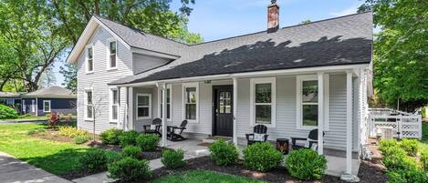 A two-story house with a porch, a chimney, and a well-maintained lawn.