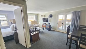 Habitación de hotel con cama, escritorio, silla, televisor, chimenea y puerta corrediza al balcón.