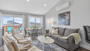 A spacious living room with a grey sofa, a coffee table, and a dining area with chairs and a table.