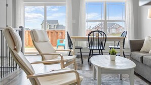 A bright living room with a large window, a dining area, and a sofa.
