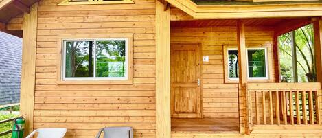 A wooden cabin with a porch, two chairs, and a table.