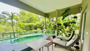 A poolside area with a table and chairs, a lounge chair, and a view of lush greenery. - Tree Scape Mountain View Resort (Hang Dong)