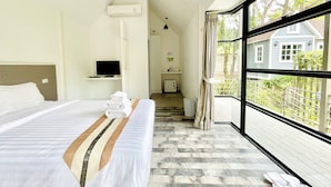 A hotel room with a large bed, a television, a window with a view of the outside, and a small kitchenette. - Tree Scape Mountain View Resort (Hang Dong)