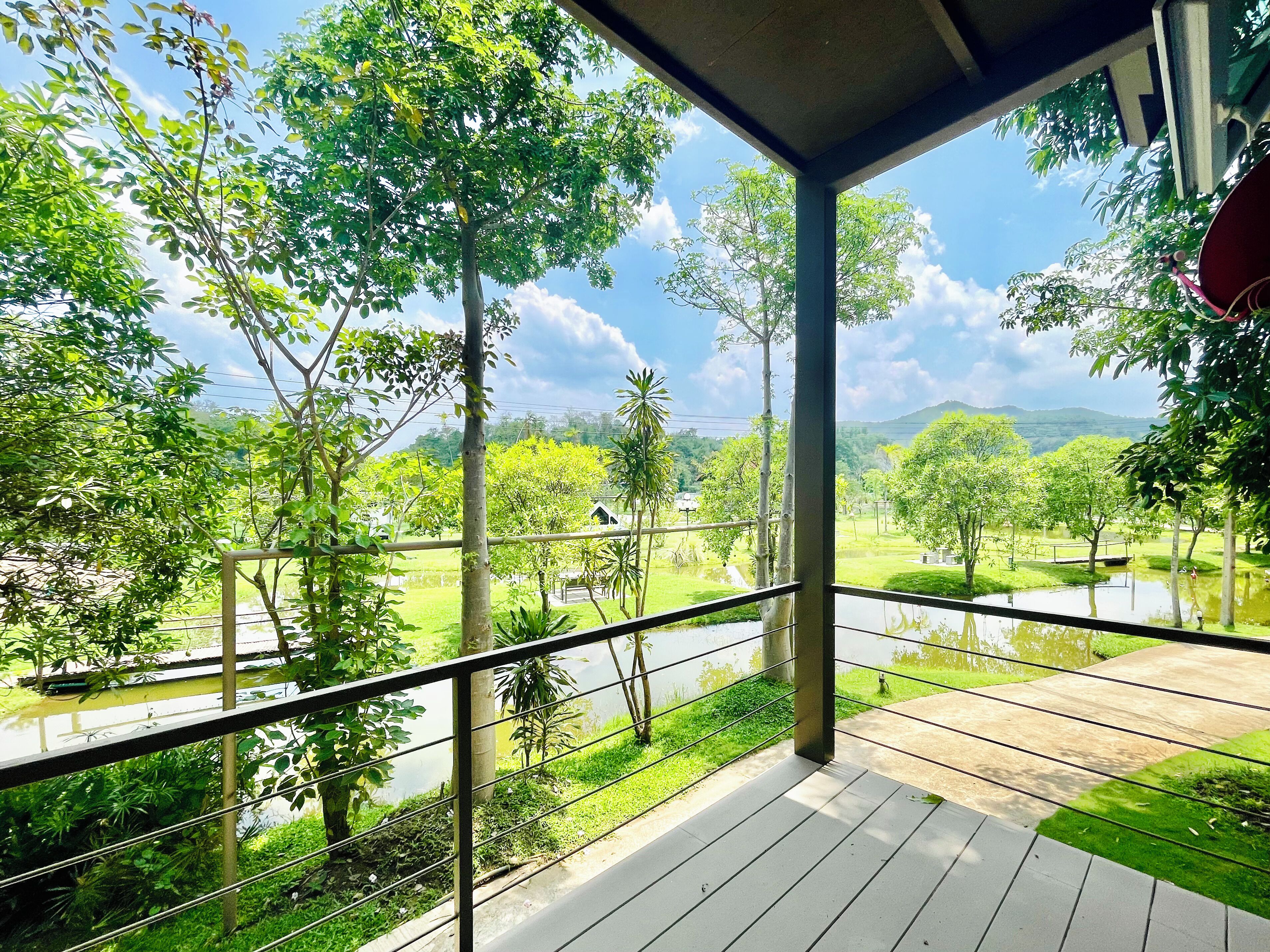 A balcony with a view of a lush green landscape, including trees and a body of water.