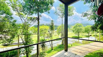 A balcony with a view of a lush green landscape, including trees and a body of water.
