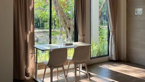 A room with a large window, a table with chairs, and a door. - Tree Scape Mountain View Resort (Hang Dong)
