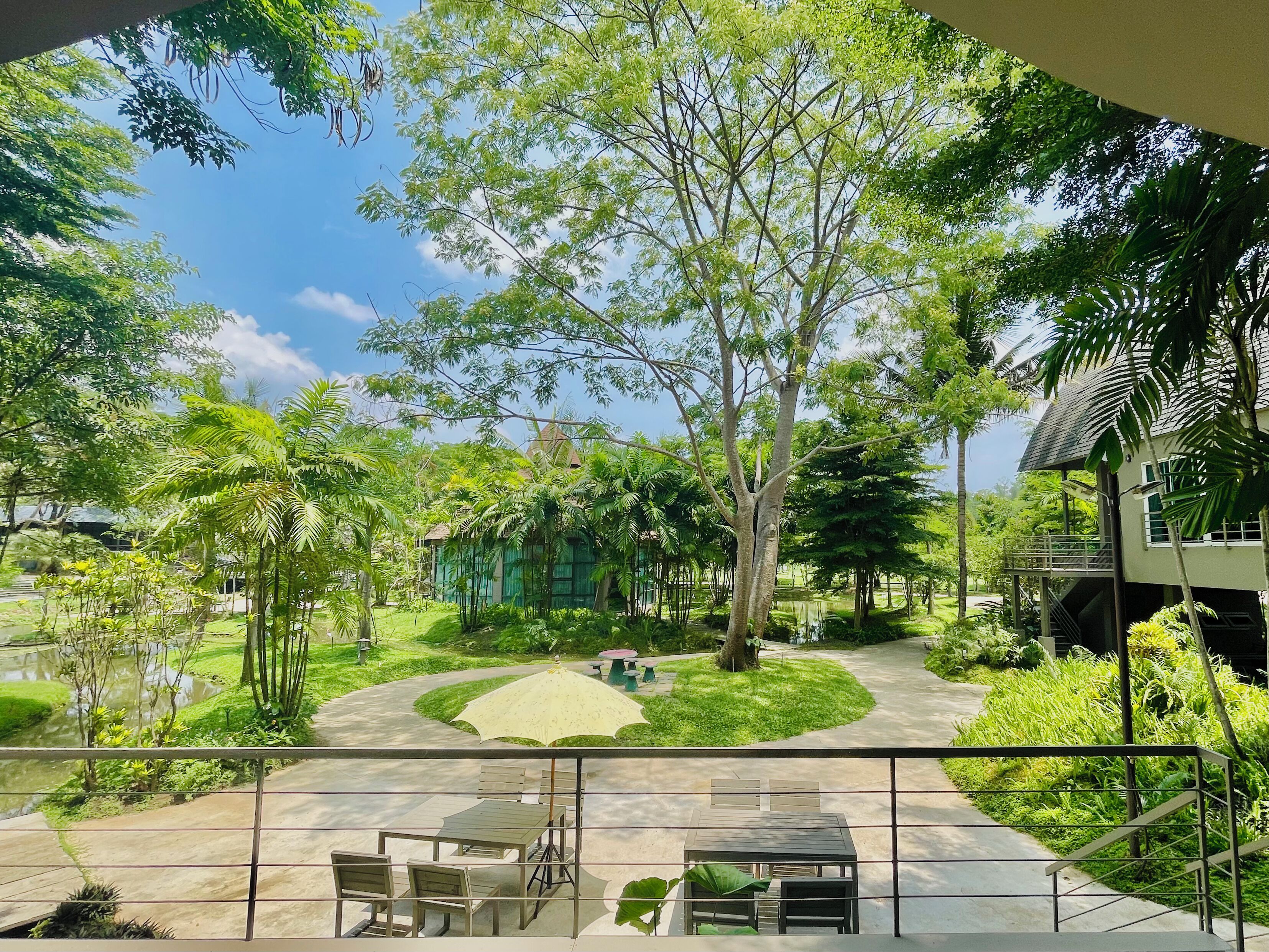 Un patio con una zona de estar central, rodeado de exuberante follaje y árboles.
