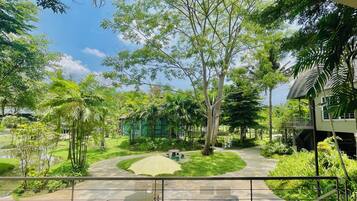 Un patio con una zona de estar central, rodeado de exuberante follaje y árboles.