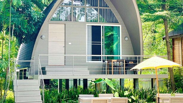A modern, curved-roofed building with a balcony and outdoor seating area. - Tree Scape Mountain View Resort (Hang Dong)