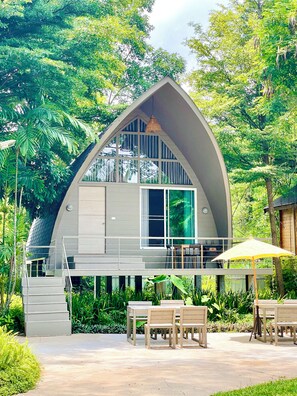 A modern, curved-roofed building with a balcony and outdoor seating area. - Tree Scape Mountain View Resort (Hang Dong)