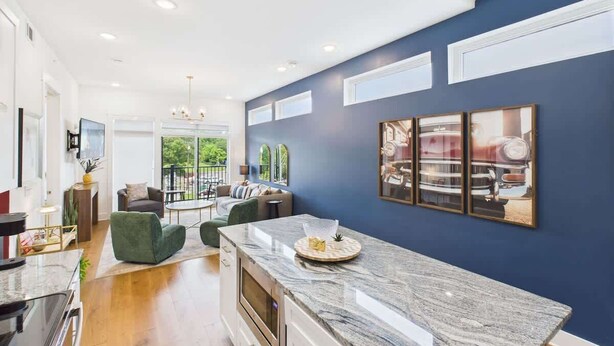 A modern kitchen with a marble countertop, a dining area with a sofa and chairs, and a large window offering a view of the outdoors. - Gallatin Retreat-Rooftop- Full Gym -East Nashville (Nashville)