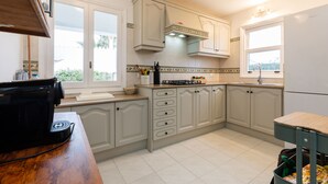 A kitchen with white cabinets, a black coffee maker, and a window with a view of greenery.
