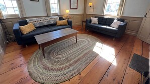 Ein Wohnzimmer mit zwei Sofas, einem Couchtisch und einem gemusterten Teppich.