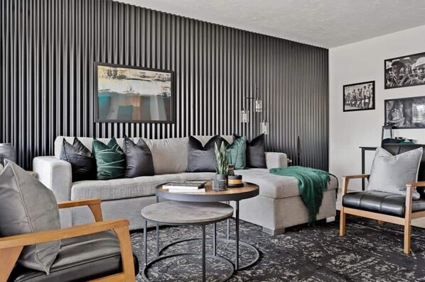 Una sala de estar moderna con un sofá gris, una mesa de centro redonda y una alfombra estampada.