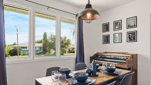 Ruokailutilassa on piano, neljälle katettu ruokapöytä ja suuret ikkunat, joista on näkymä ulos.