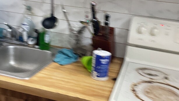 Una cocina con armarios de madera, un lavamanos de acero inoxidable, una estufa y varios utensilios de cocina.