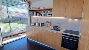 Una cocina moderna con armarios de madera, horno empotrado y ventana con persianas.