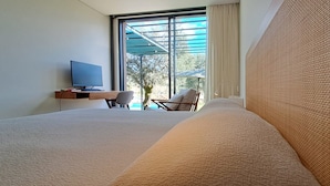 Habitación de hotel con una cama grande, un escritorio con computadora y vista al exterior.