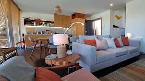 Una sala moderna con un sofá gris, una mesa de centro de madera y un comedor con una mesa y sillas de madera.