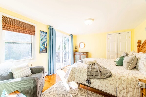 A bedroom with a bed, a sofa, a window with curtains, a bedside table, and a wardrobe.